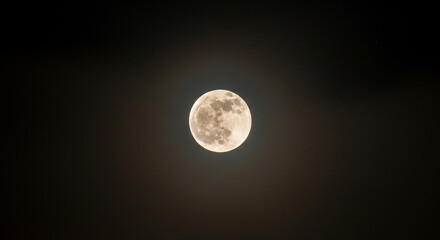 Bright full moon illuminates the dark night sky with its ethereal glow and visible details.