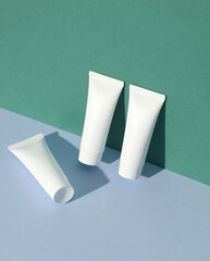 White cream tubes on colored background with shadow. Creative beauty layout. Mockup, template for design