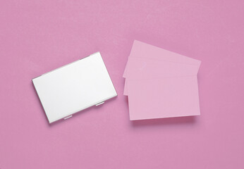 Metal box business card holder with business cards on a pink background