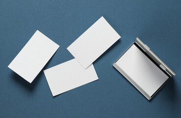 Metal box business card holder with business cards on classic blue background. Top view