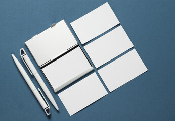 Metal box business card holder with business cards and pen on classic blue background. Top view