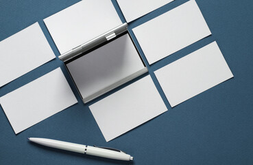 Metal box business card holder with business cards and pen on classic blue background. Top view