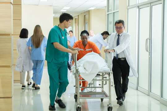 Hospital, healthcare, medical, doctor, nurse staff transports patient on gurney down hospital corridor, coordinating fast response with skilled teamwork in multiracial emergency care illness situation