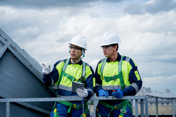 Two men in safety gear are looking at a tablet