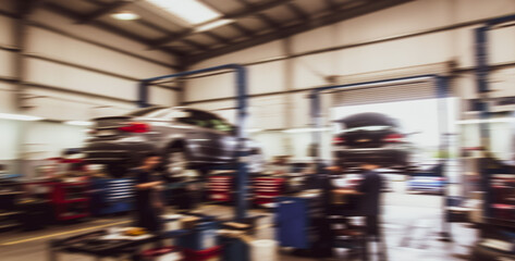 Car repair shop interior with vehicles on lifts and mechanics working.