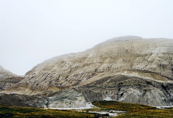 Layers of soft clay and stone rise into the haze at White Butte, North Dakota. The muted evening light highlights the land’s erosion lines and subtle color shifts across the barren hillside.