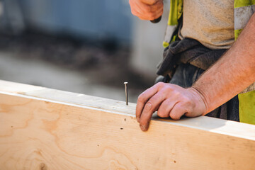 Close-up of hands of builder joiner using plywood and timber to asseble shutter panel for concrete...