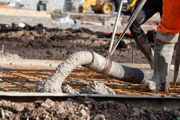 Close-up of Concreters builders using concrete pump to pour wet concrete at building site