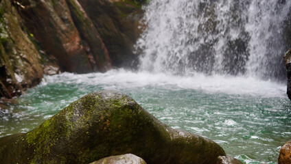A steady waterfall flows through a rich green jungle landscape, capturing the raw beauty and...