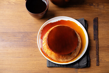 Caramel custard flan in the plate on a wood background