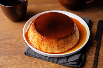 Caramel custard flan in the plate on a wood background