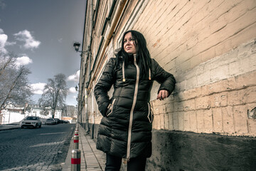 Woman lean on an old building with a shabby brick wall on a long street