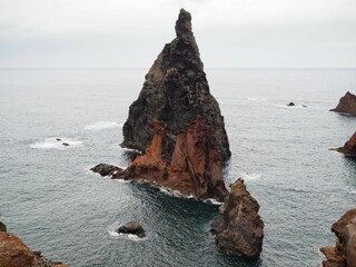 Desert landscapes of Cape Sao Lourenco. A large black triangular rock in the ocean. Nature of...