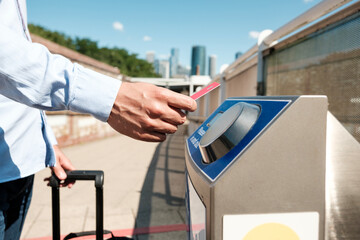Businessman using electronic ticket gate accessing public transport with travel suitcase
