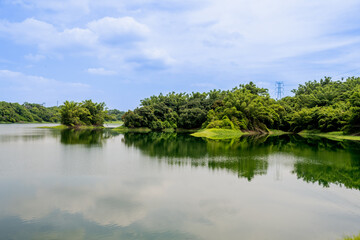 Tranquil morning view across Lantan Reservoir’s glassy water, lush tree-lined banks and soft summer sky reflecting the serene beauty of this popular scenic lake and recreation area.