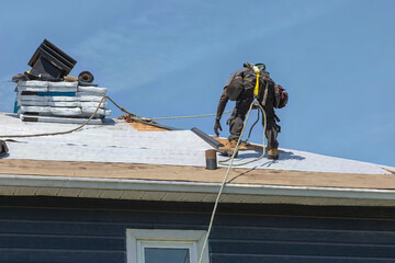 Construction Worker Installing Asphalt Shingles on House Roof