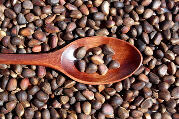 There is a wooden spoon with pine nuts.