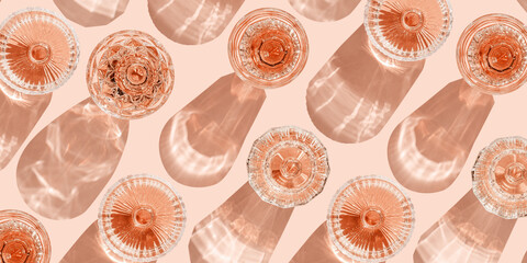 Minimal summer party banner, glasses of rose wine or champagne on pink with shadows and light reflections. Bright shine wineglass with sparkling alcohol drink at sunlight, top view monochrome pattern © yrabota