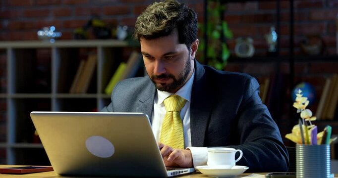 Indian businessman typing on smartphone while sitting at modern office desk, Asian corporate executive using mobile device for communication, multitasking, messaging, digital business correspondence
