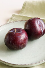 Minimalist still life with plums in bowl on table neutral colors. Food, fruits background.Copy space