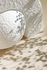 White stone pedestal, product presentation podium, template, beige background, floral shadow. Abstract minimalist concept, empty podium display product, showcase for cosmetic products . Copy space