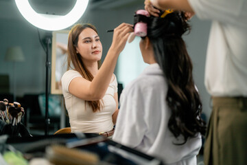 Makeup artist applying makeup on model face in dressing room