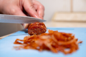 Slicing chorizo sausage on cutting board
