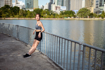 Obraz premium Woman Enjoying a Sunny Day by the Lakeside in an Urban Setting, Showcasing Fitness and Wellness