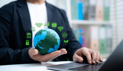 Businessman holding globe model with green technology icons representing sustainability digital...
