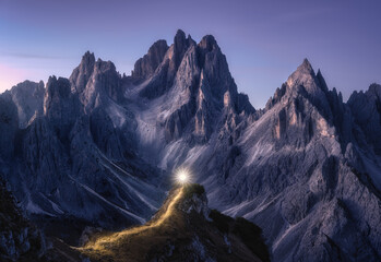 Flashlight trails on mountain path against high rocks at night in autumn. Tre cime, Dolomites,...