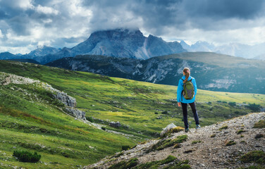 Young woman backpacker standing on a mountain path, soaking in the stunning views of the Italian...