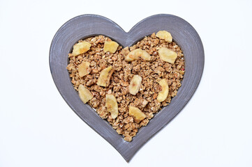 granola with freeze-dried banana in a heart-shaped frame on a white background