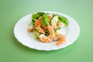 Shrimp salad with greens and cucumber slices on a green background
