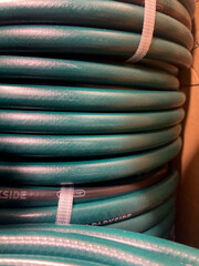 Tightly stacked coils of a dark green hose, secured with a strap, showcasing texture and industrial...