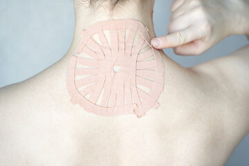 Female adult with therapeutic tape on neck for pain relief and muscle support.