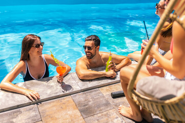 Group of Young People Hanging Out and Drinking Cocktails by the Pool