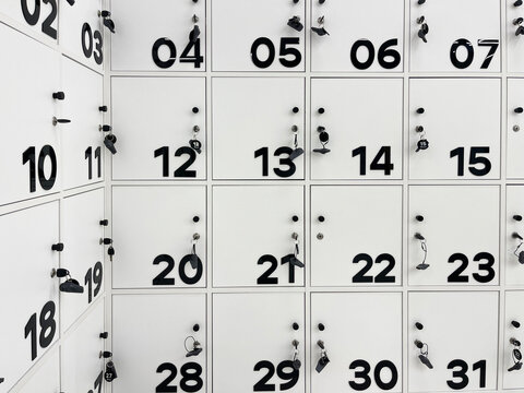 Rows of modern, white lockers with bold black numbers and keys, indicating a secure storage area in a contemporary setting