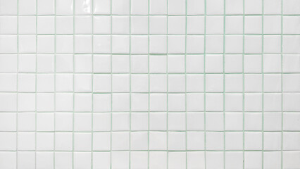 White square tile with mint green grout wall texture background. Clean ceramic bathroom or kitchen surface. Modern home interior design.