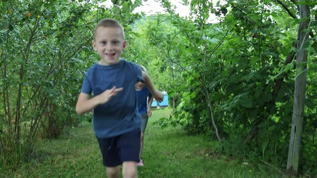 Two cute boys hang out, run and compete in their grandfather's garden. summer, fun, family visits, children's activities. Inclusion, diversity, kids with disabilities. 