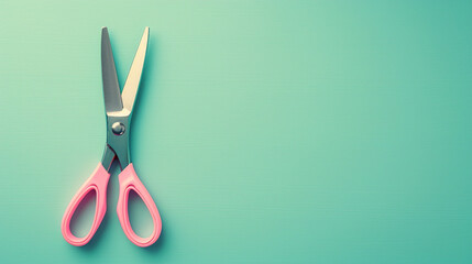 A small pair of craft scissors with pink handles placed on the left side of a pastel mint green background, top-down flat lay.