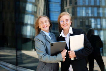 Two professionals share a joyful moment outside modern office buildings during a sunny day in the city while showcasing their teamwork and enthusiasm