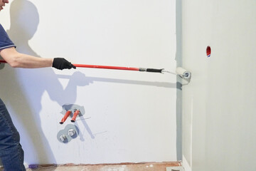 A close-up of a man's hand painting a wall white with a paint roller. Apartment painting, renovation. With space to copy. High quality photo