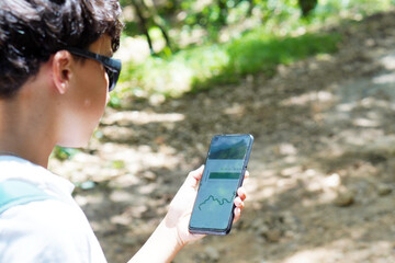 healthy living and technology. preteen boy watching on a mobile app the gps mountain route he is...