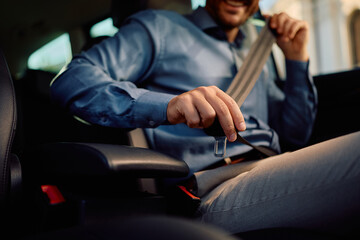 Close up of driver fastening seatbelt in car.