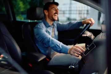 Close up of man turning up music on radio while driving car.