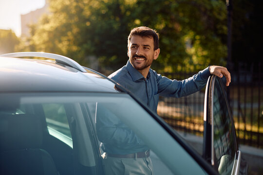 Happy businessman getting into his car.