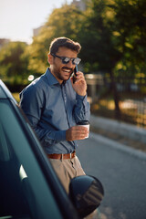 Happy man talking on mobile phone next to his car in city.