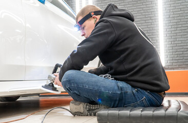 Car detailing series: Polishing white car. A master polishes the surface of a car body. Master...