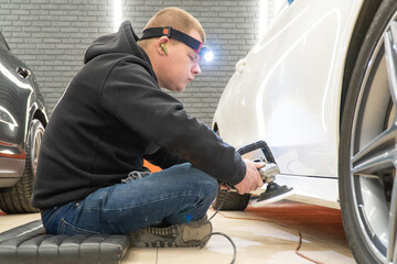 Car detailing series: Polishing white car. A master polishes the surface of a car body. Master...