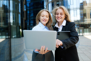 Two professionals collaborate outdoors, showcasing digital technology in a modern urban setting during a sunny day